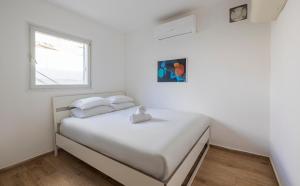 a white bedroom with a bed with a window at Alapark - MORE apartments in Beer Sheva