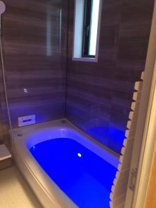 La salle de bains est pourvue d'une baignoire bleue et d'une fenêtre. dans l'établissement HONRENGA石垣島, à Ishigaki