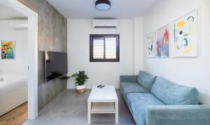 Alapark - MORE apartments في بئر السبع: غرفة معيشة مع أريكة زرقاء وطاولة