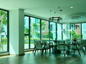 a dining room with a table and chairs and windows at Near Central Festival- 5mims Walk- Infinity Pool & Comfort Room@The One Chiang Mai Condo in Chiang Mai