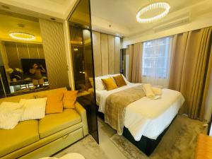 a bedroom with a bed and a couch and a mirror at Yassi's Suite at MOA in Manila