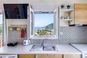 a kitchen with a sink and a window at Aloupi Pool Apartment in Skopelos Town +17 photos
