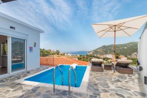 a villa with a swimming pool and an umbrella at Aloupi Pool Apartment in Skopelos Town