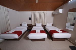 a room with three beds and a mirror at DREAMS AIRPORT RESIDENCY in Nedumbassery