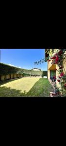 un gran campo de hierba con un edificio y flores en El Acebu, en Colombres