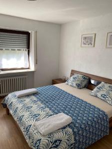 Schlafzimmer mit einem Bett mit blauer und weißer Bettwäsche und einem Fenster in der Unterkunft Gemütliche Gäste Suite für ruhige Nächte. Zentral in Ichenhausen