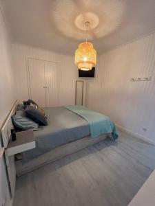 a bedroom with a bed and a chandelier at Bluebay Sesimbra - Laura in Sesimbra