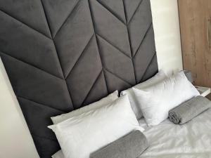1 dormitorio con cabecero negro grande y almohadas blancas en Maadima, The Yard, en Edenvale