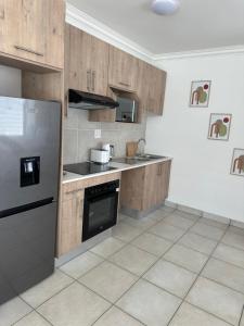 a kitchen with wooden cabinets and a stainless steel refrigerator at Maadima, The Yard in Edenvale