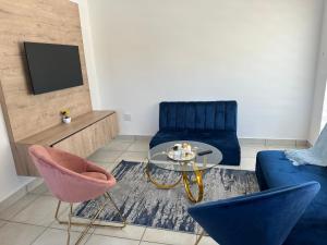 a living room with a blue couch and a glass table at Maadima, The Yard in Edenvale
