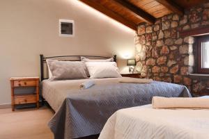 a bedroom with two beds and a stone wall at Petronas Land House 2 in Archangelos