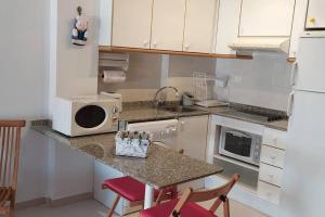 eine Küche mit einer Theke mit Spüle und Mikrowelle in der Unterkunft Precioso apartamento en Canet d,en Berenger in Canet d'en Berenguer + 9 Fotos