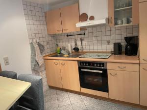 a kitchen with wooden cabinets and a stove top oven at Ferienwohnung Seewaldhof in Lauchhammer