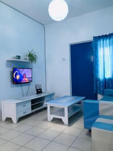 a living room with a tv and a bench at The Cave in Tanah Rata