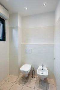 a white bathroom with a toilet and a sink at FrenkHome open space in Riolo