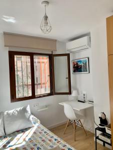 1 dormitorio con 1 cama, escritorio y ventanas en Habitación González, en Málaga