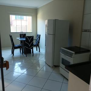 a kitchen with a refrigerator and a table and chairs at Casa Cidade Nova, Jd Belvedere. in Volta Redonda