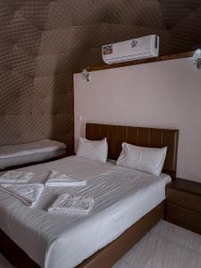 a bedroom with a bed with white sheets and aperature at rum rema camp in Wadi Rum