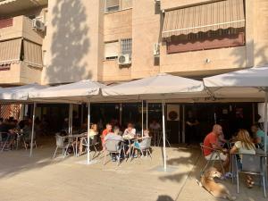 un grupo de personas sentadas en mesas bajo sombrillas en Habitación González, en Málaga