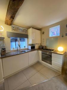 a kitchen with white cabinets and a sink and a stove at The Old Stable in Shifnal