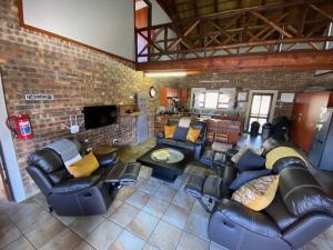 a living room with leather furniture and a brick wall at Nghala Self-catering Holiday Home in Marloth Park