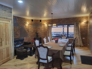 Un comedor con una mesa y sillas y una pared de ladrillos. en Pauliankos Pakalnė 1, en Krakiai