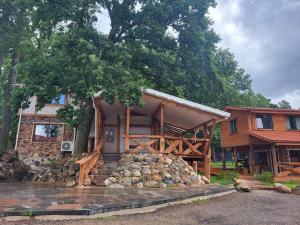 una casa de madera con una pared de piedra de retención delante de ella en Pauliankos Pakalnė 1, en Krakiai