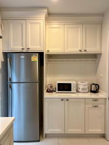 a kitchen with white cabinets and a stainless steel refrigerator at Entire 3BR Townhome in Sukhumvit, shared Pool, near BTS&MRT Asok in Bangkok