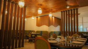 una sala da pranzo con tavoli, sedie e lampadari a braccio di فندق فاندال a Jazan