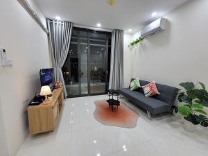 a living room with a black couch and a tv at Housinco Premium - Serviced Apartments Nguyễn Xiển Street near Tops Market in Hanoi
