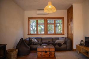a living room with a leather couch and a window at KOWHAI COTTAGE in Kaikoura