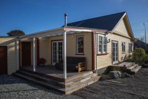 a small house with a wooden deck in front of it at KOWHAI COTTAGE in Kaikoura