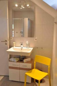 een badkamer met een wastafel en een gele stoel bij 3 Zimmer Neubauwohnung in der schwäbischen Toskana in Löwenstein