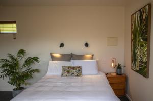 a bedroom with a large white bed with two plants at KOWHAI COTTAGE in Kaikoura