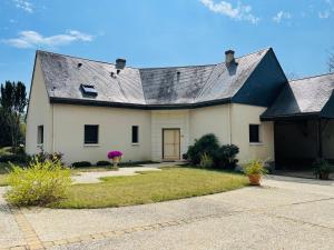 una gran casa blanca con techo negro en The Paillottes of Haute Mazère with swimming pool en Pocé-sur-Cisse