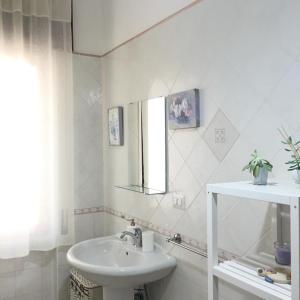 La salle de bains blanche est pourvue d'un lavabo et d'un miroir. dans l'établissement Casa Matilde, à Capaccio-Paestum