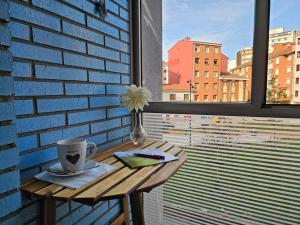una mesa con una taza de café y una flor en ella en 1A109 Cómodo y con garaje, en Gijón