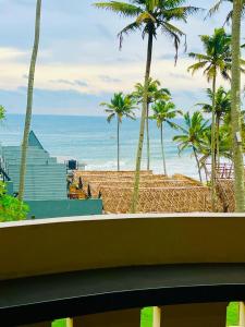 a view of a beach with palm trees and the ocean at hello beach view resorts in Varkala