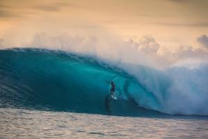 a man riding a wave on a surfboard in the ocean at Villa Onu Mentawai - Private Rooms in Katiet