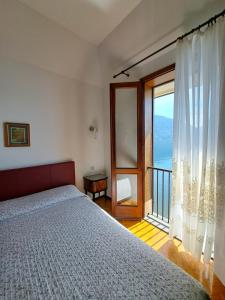 1 dormitorio con cama y ventana grande en Villa del Pescatore, en San Siro