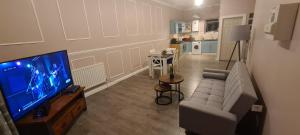 ein Wohnzimmer mit einem Sofa und einem TV sowie eine Küche in der Unterkunft Charming 1-Bed Apartment in Barnsley in Barnsley