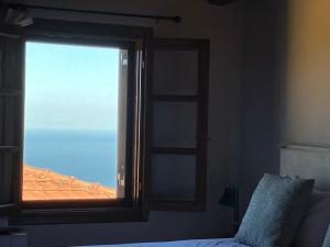 ventana en un dormitorio con vistas al océano en Melofegaro Guesthouse en Palaios Panteleimon
