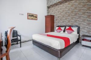 Schlafzimmer mit einem Bett mit roten und weißen Kissen in der Unterkunft OYO Life 90091 Wisma Pakuan Syariah in Bogor