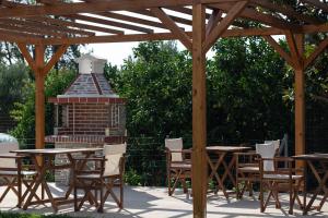 a wooden pavilion with tables and chairs and a fireplace at Diva Lodge in Sykia Chalkidikis