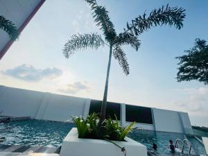 a pool with a palm tree next to a building at JC HOMESTAY RAWANG in Rawang