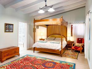 1 dormitorio con cama de madera con dosel y alfombra en Exquisite rural house with garden, pool and sea views en Arico Viejo