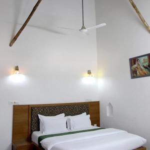 1 dormitorio con 1 cama con sábanas blancas y 2 luces en Neelkanth's Bagar Inn Resort, en Jhunjhunūn