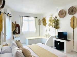 una stanza bianca con un letto e una tv di Pillow Inn Ubud ad Ubud