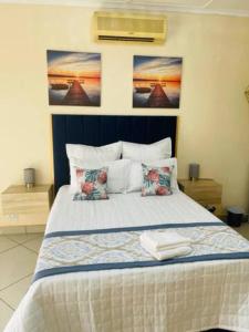 a bedroom with a bed with two paintings on the wall at Kalaji C-Rane Lodge in Phalaborwa