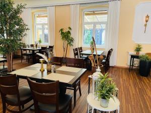 a restaurant with tables and chairs and plants at Harzhotel Warnstedter Krug in Thale
